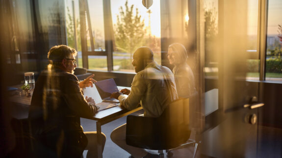 Business people collaborating on laptop in modern office.